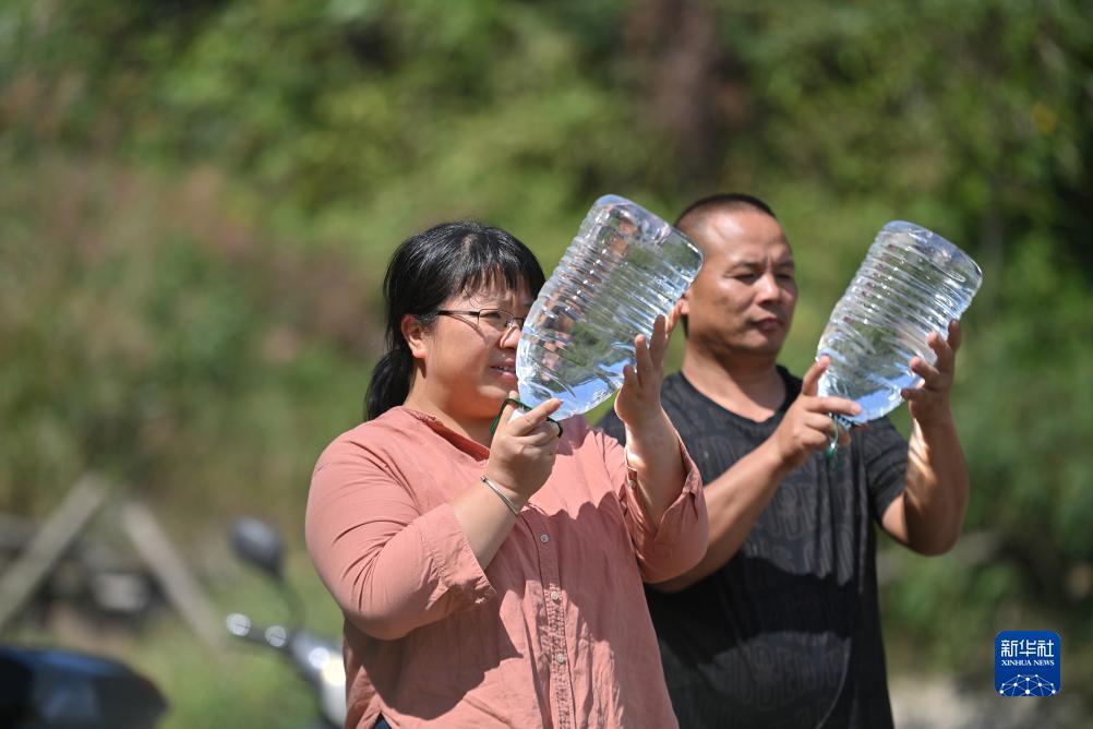 楊寧（左）在查看村民剛剛采集的水樣，為山泉水引水工程做準(zhǔn)備（10月8日攝）。新華社記者 黃孝邦 攝